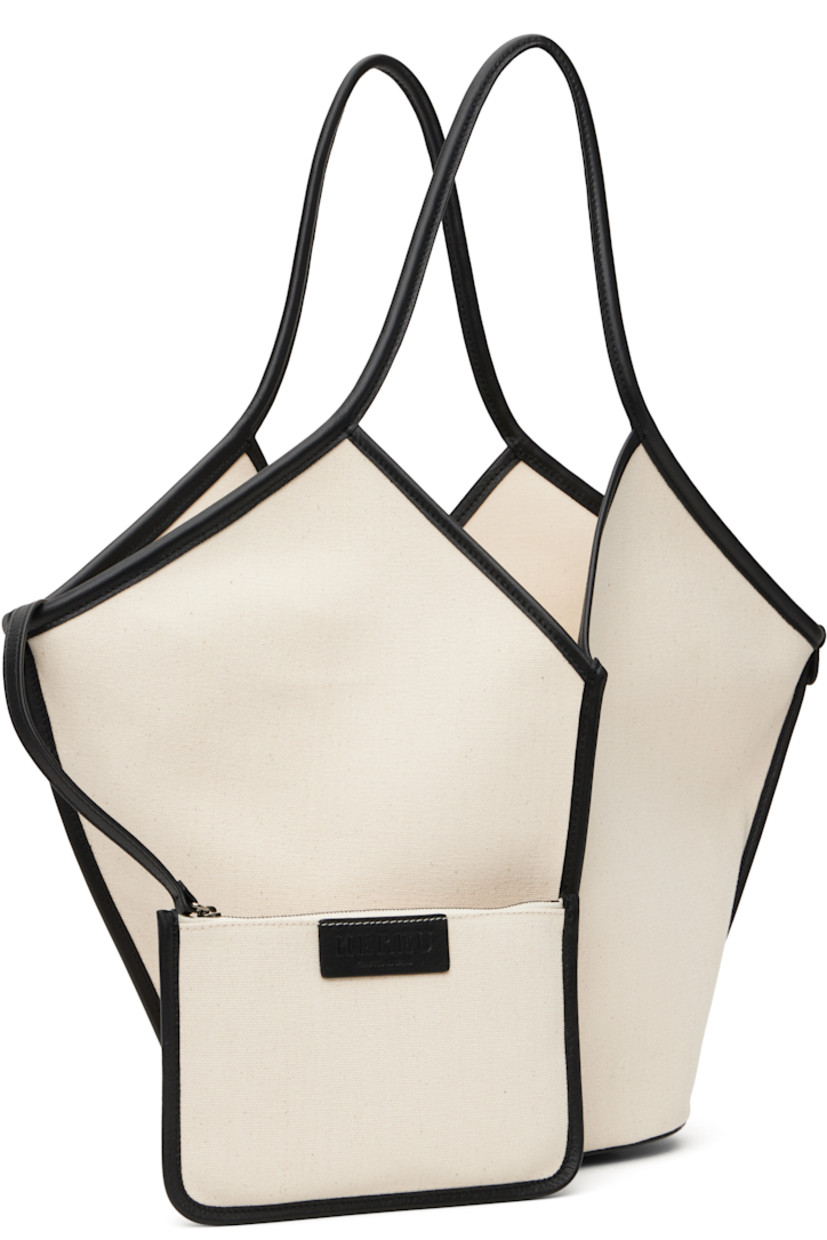 Handcrafted organic cotton canvas tote in beige and black. 

· Grained calfskin trim throughout
· Fixed twin shoulder straps
· Pinched seams at face, sides, and back face
· Bumper pads at base
· Self-tie fastening at open throat
· Detachable zip pouch at interior 
· H13" x W20" x D5"

Supplier color: Beige/Black