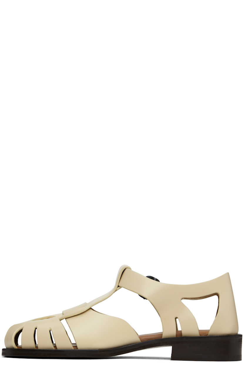 Handcrafted polished calfskin flat sandals in beige.

· Cutouts throughout
· Pin-buckle ankle strap
· Logo embossed at padded calfskin footbed
· Suede lining
· Serrated detailing at welt
· Stacked calfskin heel and midsole
· Calfskin sole with rubber injection

Supplier color: Custard