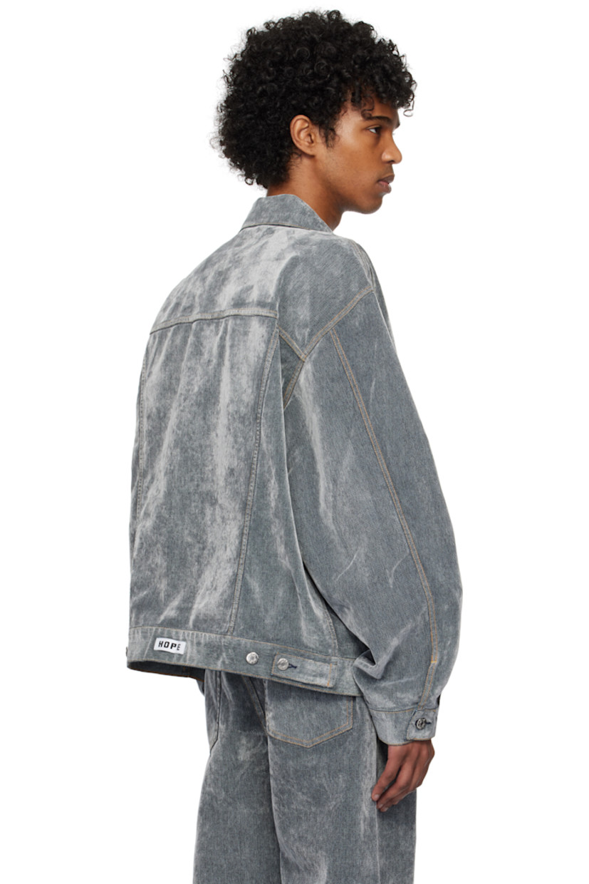 Flocked non-stretch denim jacket. 

· Spread collar 
· Button closure
· Flap pockets
· Welt pockets
· Pleat at single-button barrel cuffs
· Adjustable button tabs and logo patch at back hem
· Contrast stitching in tan 

Supplier color: Grey flock