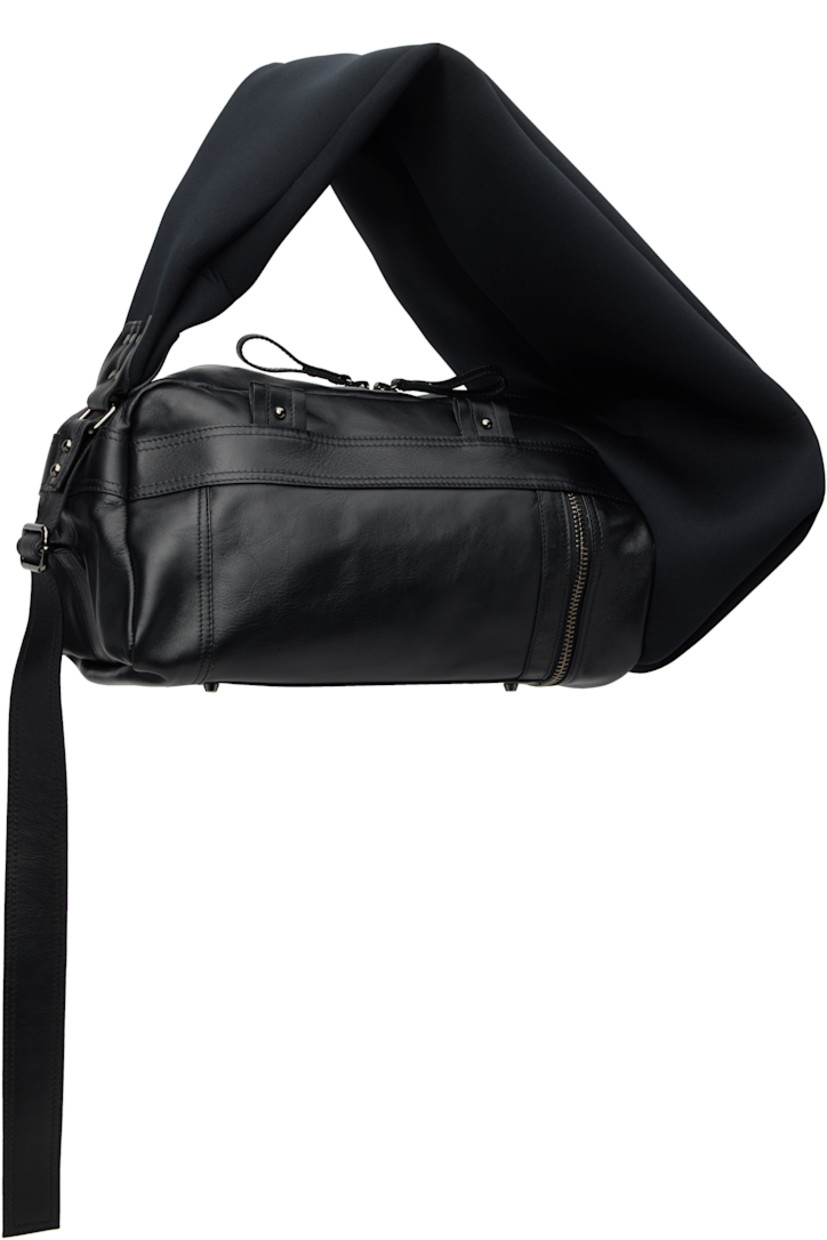 Grained leather and neoprene shoulder bag.

· Adjustable shoulder strap
· Press-stud tab with logo-engraved hardware at face
· Pull-loop at face
· Bumper studs and zip pocket at base
· Twin pull-loops at back face
· Two-way zip closure
· Zip pocket and patch pockets at interior
· Twill lining
· H8.5" x W19" x D10"

Supplier color: Black
