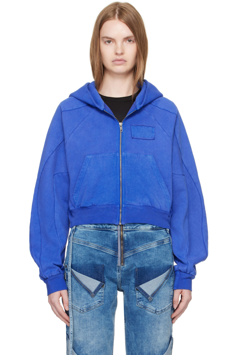 Organic cotton fleece hoodie. 

· Zip closure
· Patch with raw edge at chest
· Patch pockets
· Rib-knit cropped hem and cuffs
· Raglan sleeves
· Graphic printed at back 

Supplier color: Surf blue