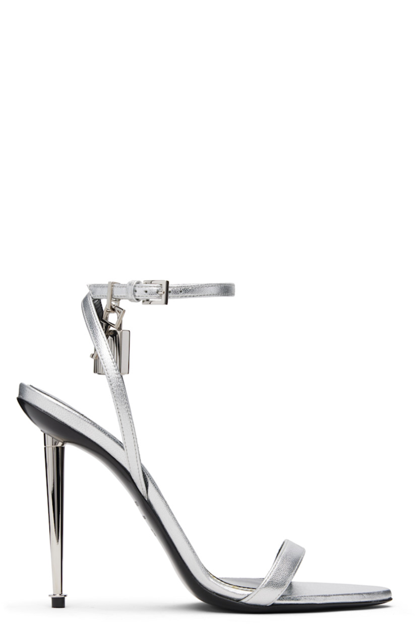 Laminated grained nappa sheepskin heeled sandals.

· Open pointed toe
· Padlock and logo charm at pin-buckle ankle strap
· Logo printed at leather footbed
· Metal stiletto heel with rubber injection
· Polished leather sole
· Logo-engraved silver-tone hardware
· Heel: H4.25"

Supplier color: Silver