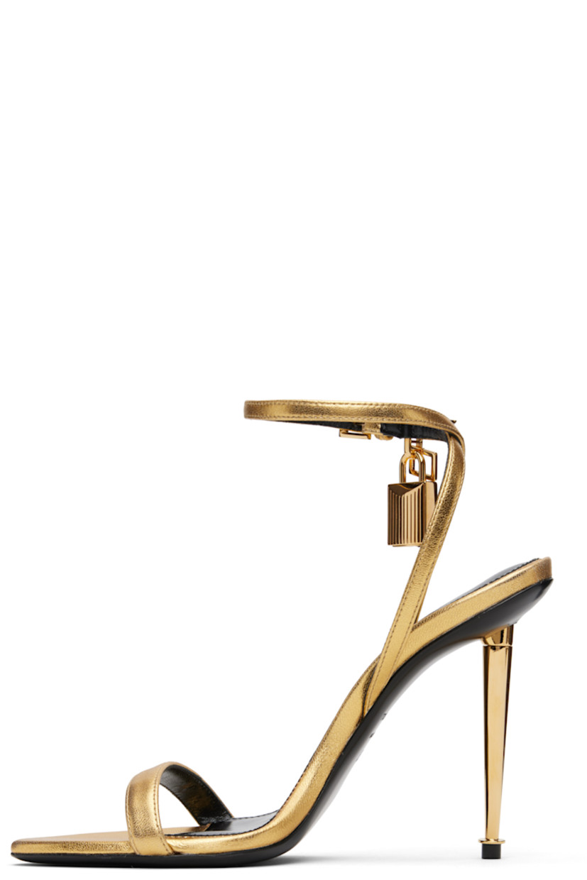Laminated grained nappa sheepskin heeled sandals.

· Open pointed toe
· Padlock and logo charm at pin-buckle ankle strap
· Logo printed at leather footbed
· Metal stiletto heel with rubber injection
· Polished leather sole
· Logo-engraved gold-tone hardware
· Heel: H4.25"

Supplier color: Gold