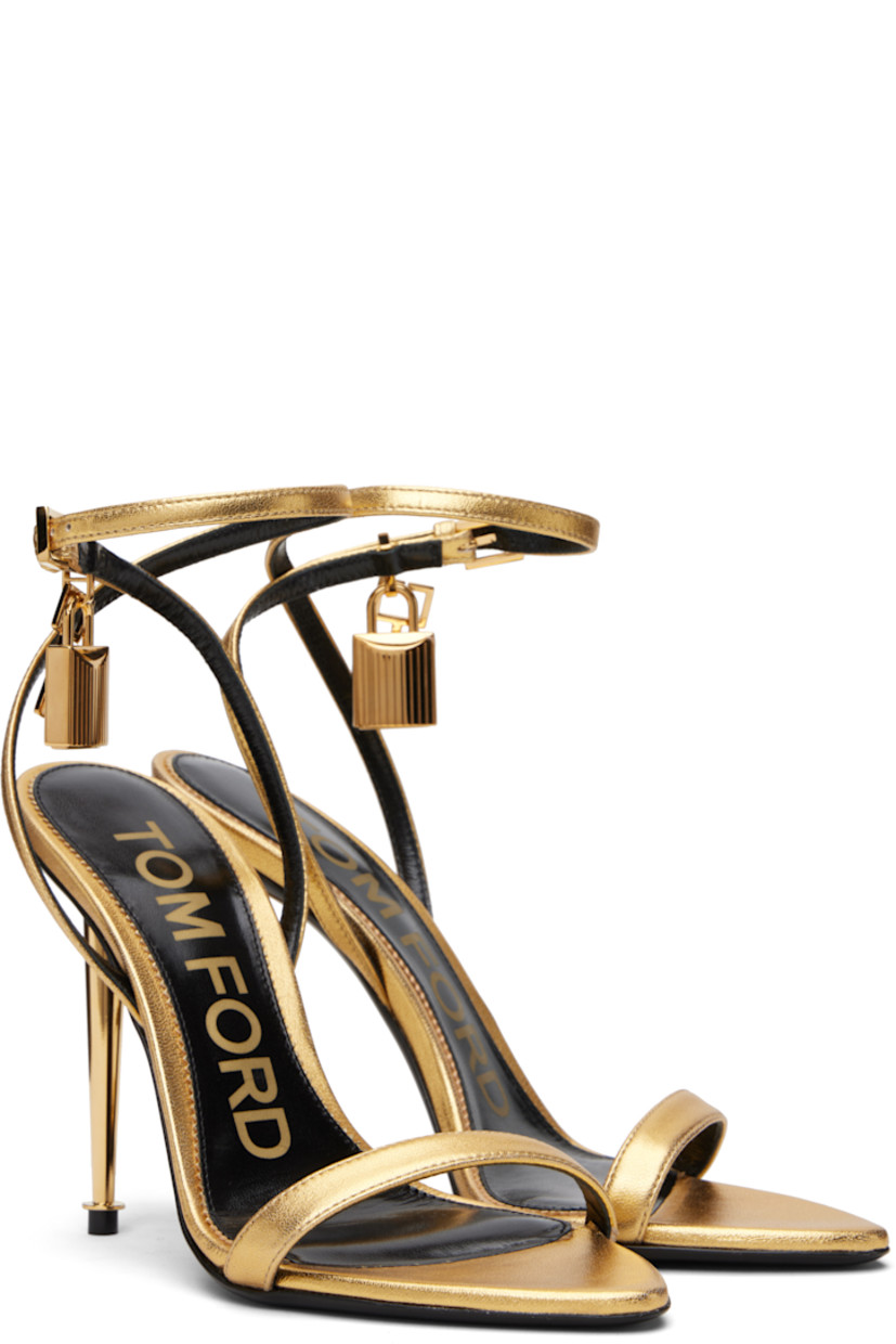 Laminated grained nappa sheepskin heeled sandals.

· Open pointed toe
· Padlock and logo charm at pin-buckle ankle strap
· Logo printed at leather footbed
· Metal stiletto heel with rubber injection
· Polished leather sole
· Logo-engraved gold-tone hardware
· Heel: H4.25"

Supplier color: Gold