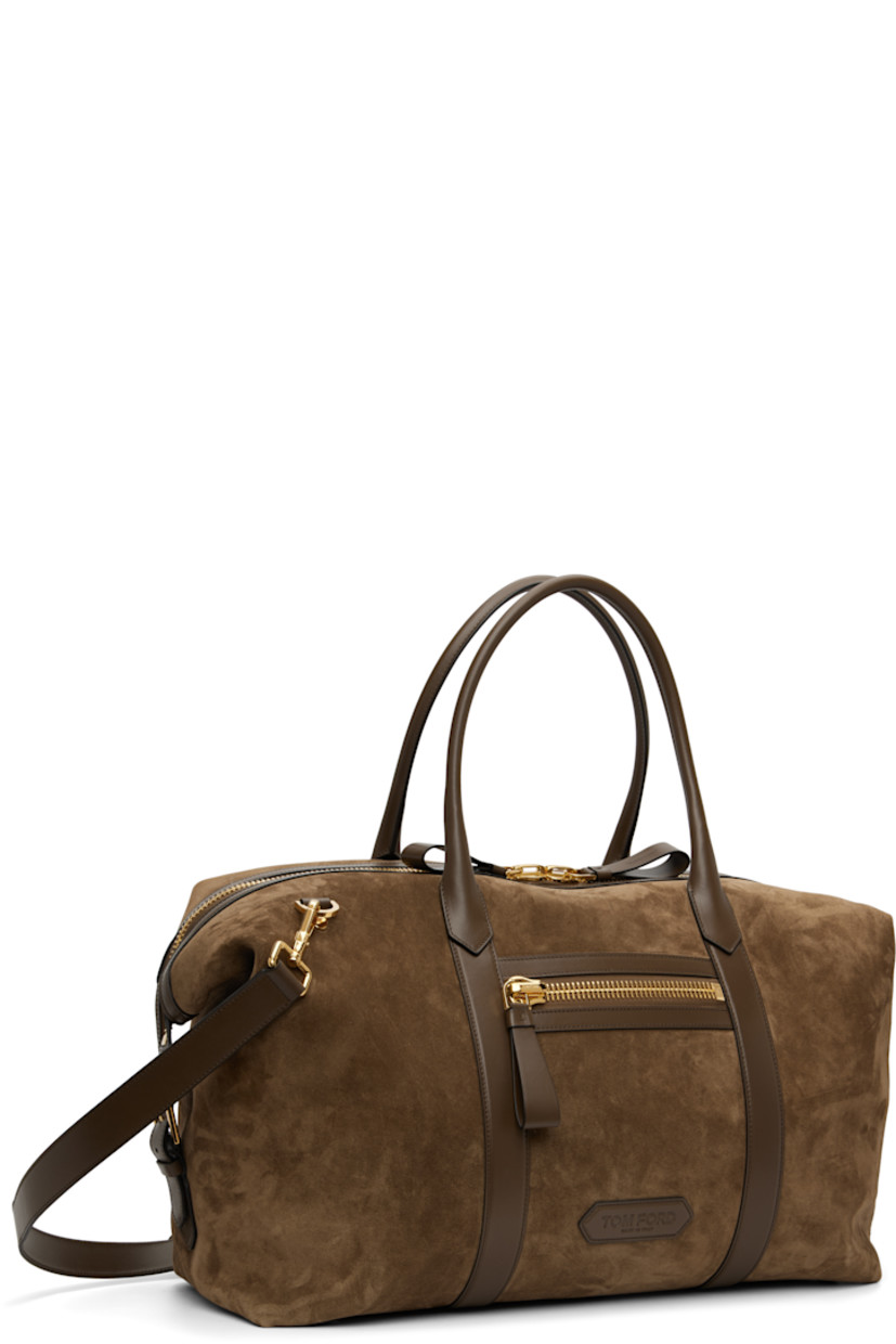 Suede calfskin duffle bag.

· Buffed calfskin trim throughout 
· Rolled carry handles
· Adjustable and detachable shoulder strap
· Zip pocket and logo patch at face
· Pin-buckle strap at sides 
· Bumper studs at base
· Two-way zip closure 
· Zip and patch pockets at interior 
· Twill lining
· Gold-tone hardware
· H14.5" x W20.5" x D7"

Supplier color: Walnut