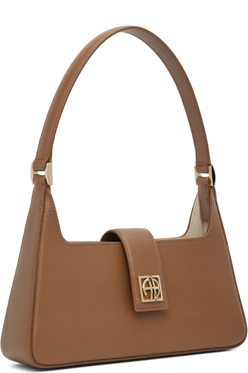 Buffed leather shoulder bag.

· Fixed shoulder strap
· Logo hardware at face
· Magnetic foldover flap
· Patch pocket at interior
· Gold-tone hardware
· H5” x W10” x D2.5”

Supplier color: Cognac