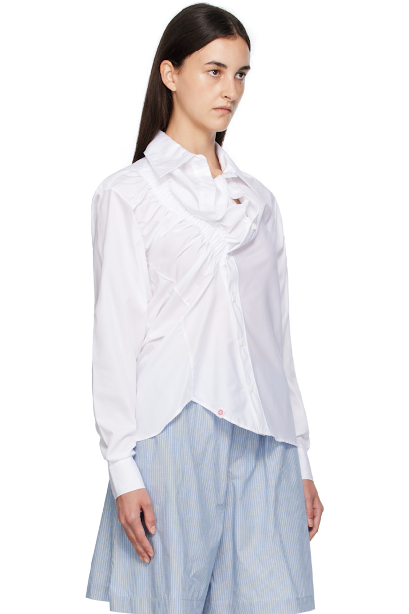 Cotton poplin shirt.

· Asymmetrical construction
· Spread collar
· Button closure
· Elasticized trim at front
· Logo flag at front hem
· Shirttail hem
· Buttoned barrel cuffs
· Box pleat at back yoke

Supplier color: White