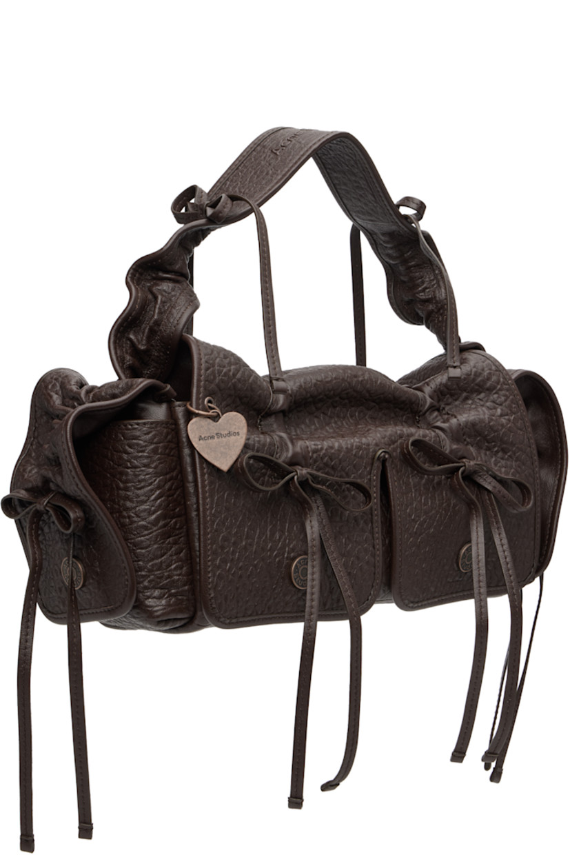 Grained nappa lambskin top handle bag.

· Bows and ruching throughout
· Embossed logo at adjustable shoulder strap
· Logo charm at face
· Flap pocket at sides
· Magnetic flap
· Patch pocket at interior
· Logo-engraved antiqued copper-tone hardware
· H6.5" x W14" x D4"

Supplier color: Chocolate brown