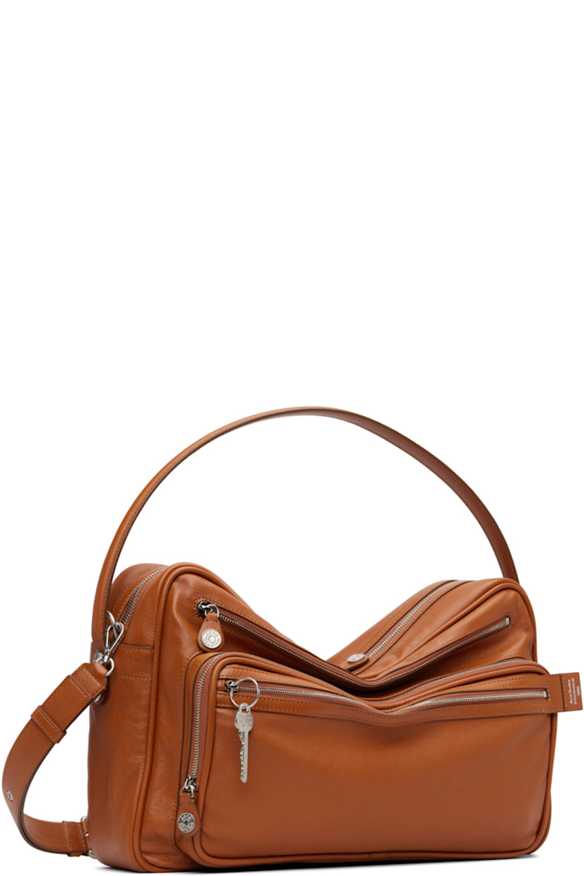 Grained calfskin shoulder bag.

· Fixed carry handle
· Adjustable and detachable shoulder strap
· Logo stamp, key charm, and zip pockets at face
· Rivet and patch pocket at back face
· Rivets at sides 
· Bumper studs at base 
· Two-way zip closure
· Patch pocket at interior 
· Buffed faux-leather lining
· Logo-engraved silver-tone hardware 
· H11" x W16" x D4.5"

Supplier color: Cognac brown