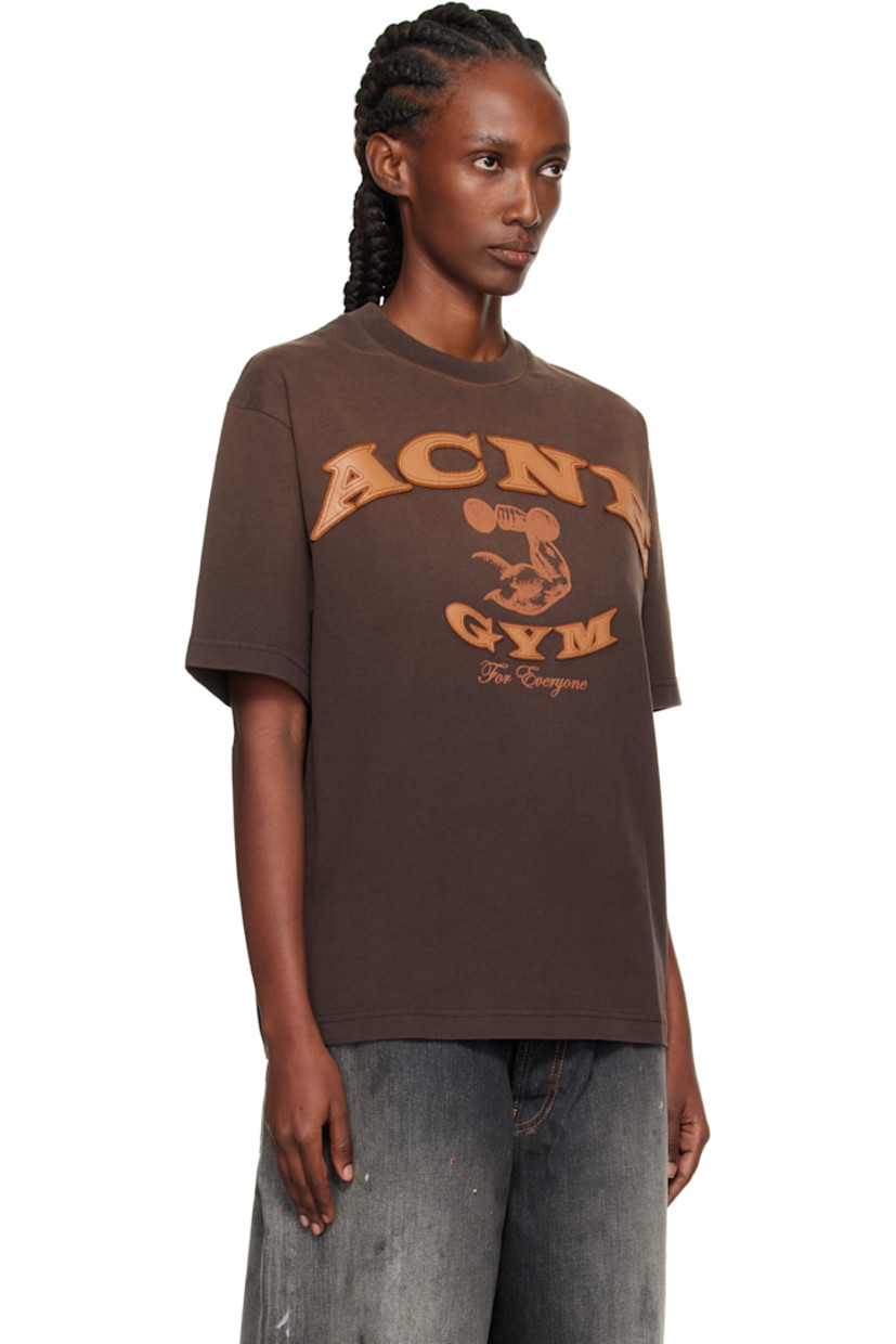 Organic cotton jersey T-shirt.

· Fading throughout
· Rib-knit crewneck
· Logo and text appliqué at front
· Graphic and text printed at front
· Dropped shoulders

Supplier color: Dark brown