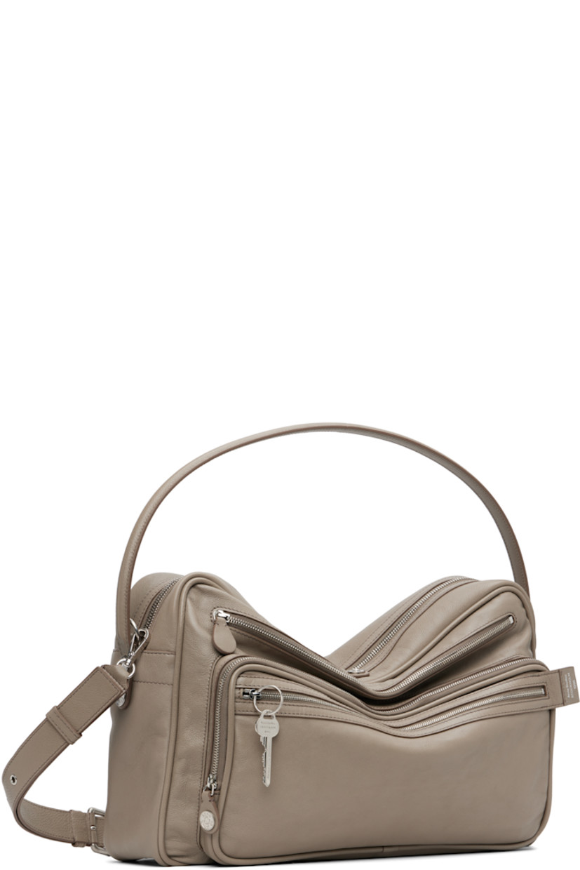 Grained calfskin shoulder bag.

· Fixed carry handle
· Adjustable and detachable shoulder strap
· Logo stamp, key charm, and zip pockets at face
· Rivet and patch pocket at back face
· Rivets at sides 
· Bumper studs at base 
· Two-way zip closure
· Patch pocket at interior 
· Buffed faux-leather lining
· Logo-engraved silver-tone hardware 
· H11" x W16" x D4.5"

Supplier color: Taupe beige
