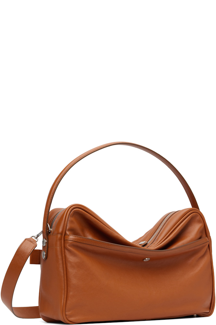 Grained calfskin shoulder bag.

· Fixed carry handle
· Adjustable and detachable shoulder strap
· Logo stamp, key charm, and zip pockets at face
· Rivet and patch pocket at back face
· Rivets at sides 
· Bumper studs at base 
· Two-way zip closure
· Patch pocket at interior 
· Buffed faux-leather lining
· Logo-engraved silver-tone hardware 
· H11" x W16" x D4.5"

Supplier color: Cognac brown