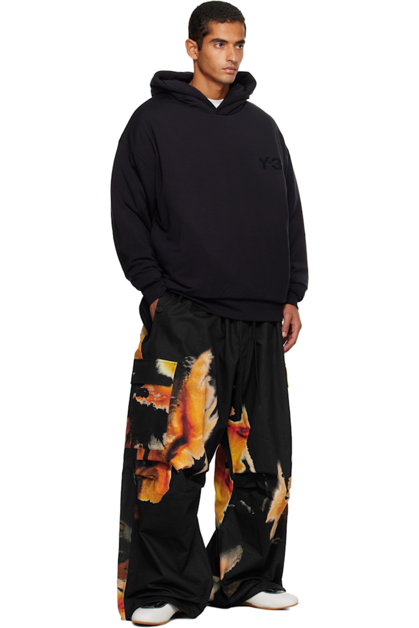 Cotton- and hemp-blend twill cargo pants.

· Loose-fit
· Graphics printed throughout
· Drawstring at elasticized waistband
· Four-pocket styling
· Zip fly
· Pleats at knees
· Drawstring at cuffs
· Cargo pocket at outseams
· Logo bonded at cargo pocket

Each item is unique. Please note coloration may vary.

Supplier color: Black