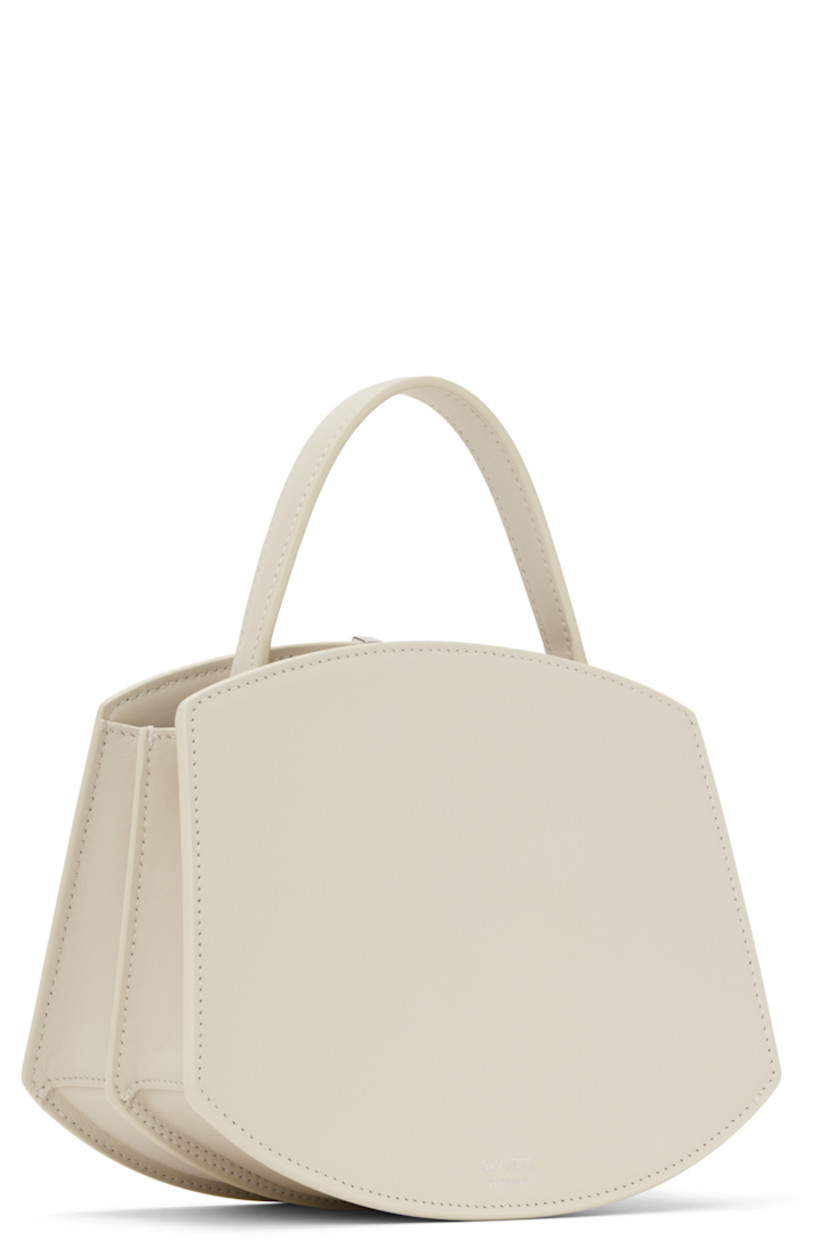 Structured buffed calfskin top handle bag in off-white.

· Carry handle at top
· Silver-tone hardware at face
· Accordion panel at sides
· Silver-tone logo stamp at back face
· Magnetic tab closure 
· Card slot at two compartment interior
· Buffed calfskin lining
· H6.75" x W8.25" x D4"

Supplier color: Ivory