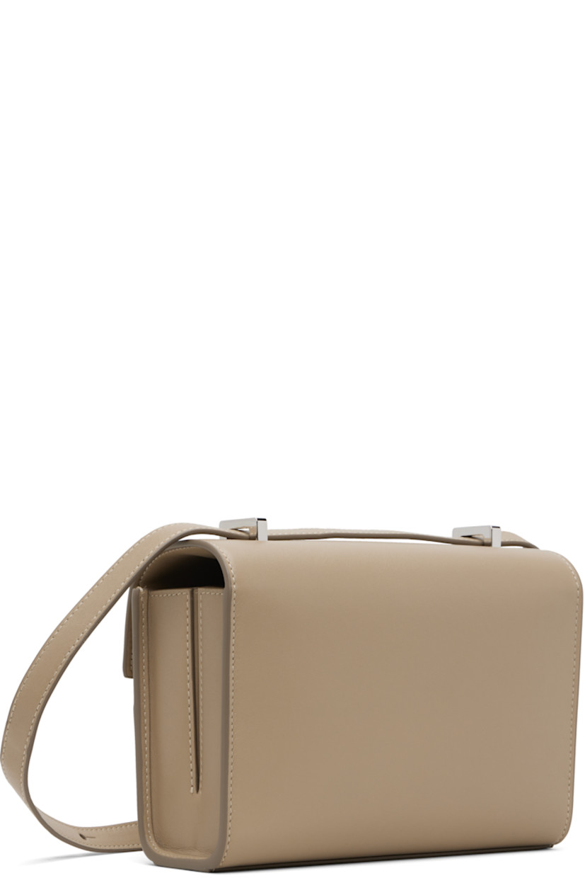 Rigid buffed calfskin shoulder bag.

· Adjustable crossbody strap
· Shorten to shoulder strap with interior studs
· Foldover flap with turn-lock clasp
· Two-compartment leather interior
· Two patch pockets
· H5.5" x W7.5" x D2.75"

Supplier color: Clay