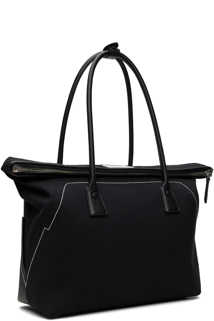 Canvas and grained calfskin shoulder bag.

· Press-stud tab at rolled shoulder straps
· Logo patch at face
· Topstitching at face and back face
· Bumper studs at base
· Foldover zip closure
· Zip pocket at interior
· Twill lining
· H13.5" x W15" x D4"

Supplier color: Black
