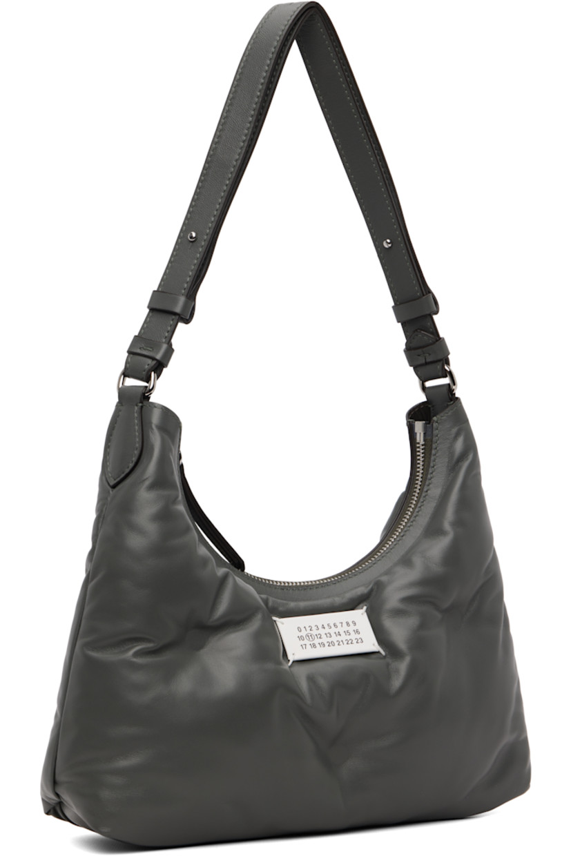 Tufted grained sheepskin shoulder bag.

· Adjustable shoulder strap
· Logo patch and white stitching at face 
· Zip closure
· Zip pocket at interior 
· Plain-woven lining 
· Silver-tone hardware
· H6" x W10.5" x D3"

Supplier color: Caillou
