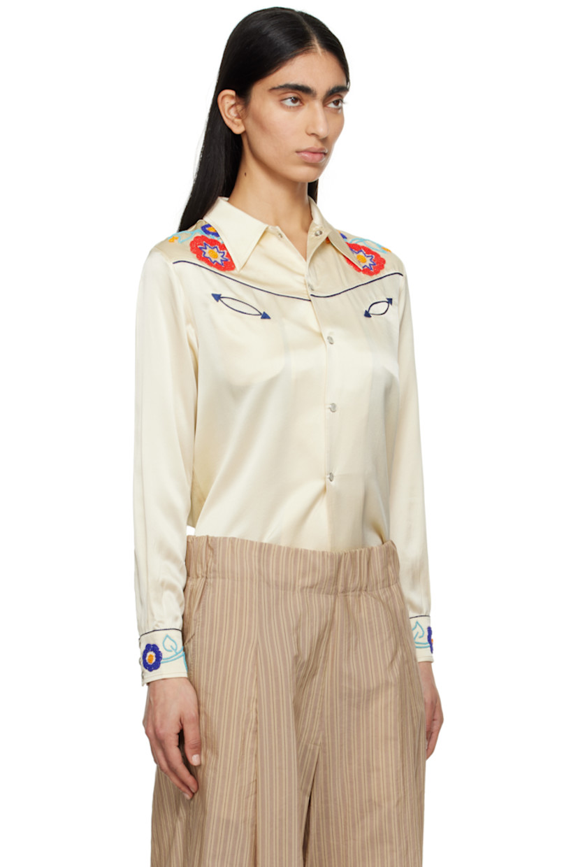 Silk satin shirt. Piping and beaded detailing throughout. 

· Spread collar
· Press-stud closure
· Western yoke at front and back
· Welt pockets
· Pleats at buttoned barrel cuffs

This item is part of a limited run of 72.

Supplier color: Cream multi