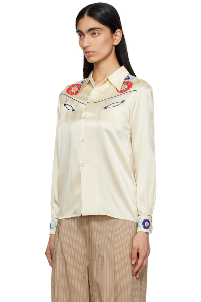 Silk satin shirt. Piping and beaded detailing throughout. 

· Spread collar
· Press-stud closure
· Western yoke at front and back
· Welt pockets
· Pleats at buttoned barrel cuffs

This item is part of a limited run of 72.

Supplier color: Cream multi