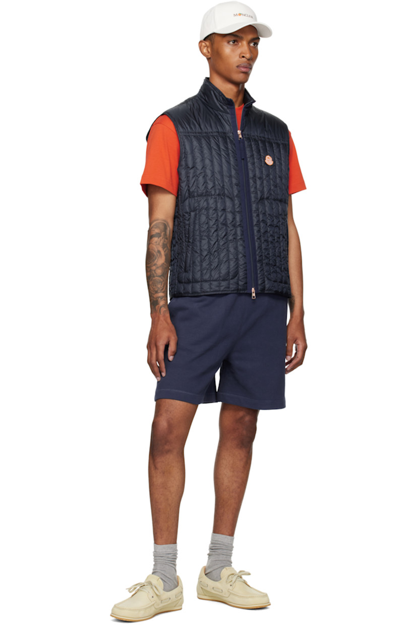 Down-filled and quilted nylon satin vest.

· DIST-certified down
· Stand collar
· Two-way zip closure
· Embroidered logo patch at chest
· Zip pockets
· Fully lined

Part of the Moncler Genius x Gilga Farm collaboration.

Supplier color: Dark navy blue

Fill 1: 90% goose down, 10% feather. Fill 2: 100% polyester.