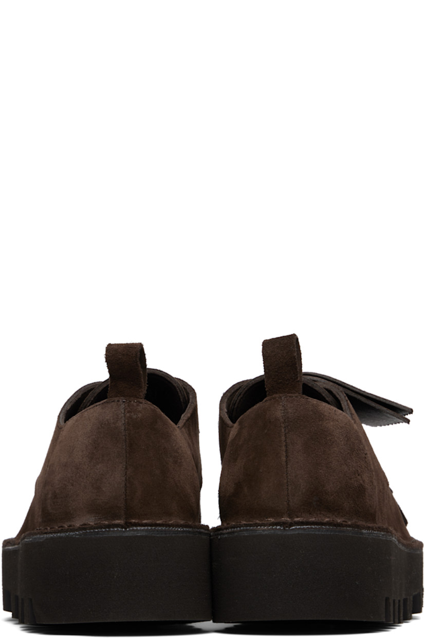 Suede derbys in brown.

· Detachable kiltie-style panel at vamp
· Logo tags at lace-up closure
· Pull loop at heel counter
· Suede lining
· Treaded Vibram® Vi-Lite rubber sole
· Heel: H1.75"

Part of the Engineered Garments x Clarks Originals collaboration.

Supplier color: Brown suede