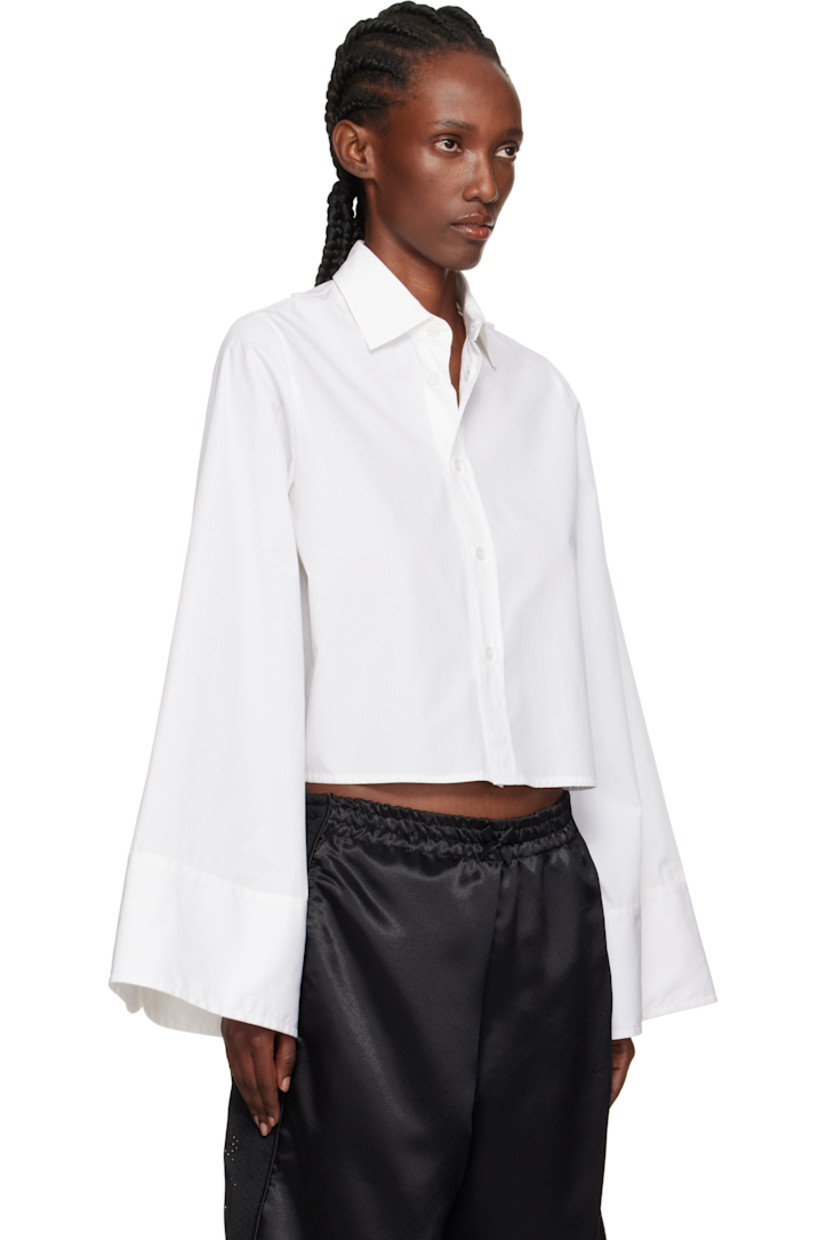 Cotton poplin shirt. 

· Spread collar
· Button closure
· Cropped hem 
· Button hardware at shoulders
· Buttoned barrel cuffs
· White stitching at back collar 

Supplier color: White
