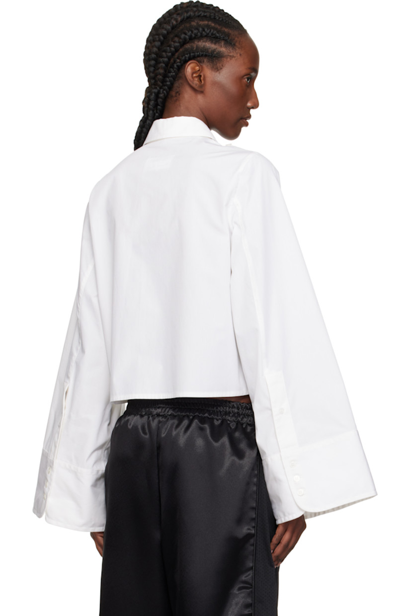 Cotton poplin shirt. 

· Spread collar
· Button closure
· Cropped hem 
· Button hardware at shoulders
· Buttoned barrel cuffs
· White stitching at back collar 

Supplier color: White