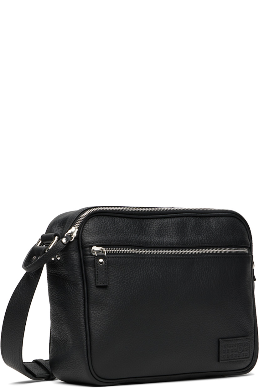 Grained calfskin messenger bag.

· Adjustable crossbody strap
· Logo patch and zip pocket at face
· White stitching at back face
· Bumper studs at base
· Two-track zip closure
· Patch pocket at interior
· Faux-suede lining
· H9" x W12" x D4"

Supplier color: Black