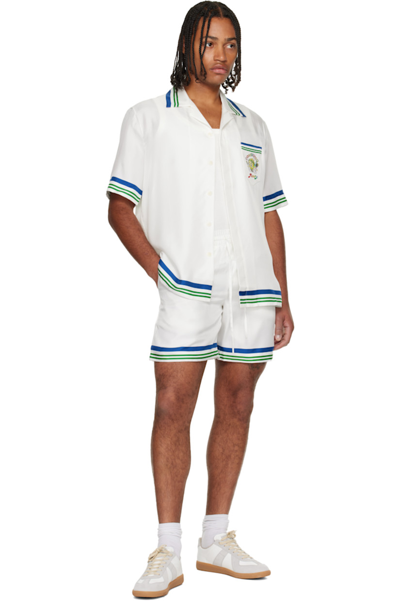 Silk twill shirt. 

· Stripes at collar, hem, and cuffs 
· Button tab at open spread collar 
· Button closure 
· Patch pocket at chest 
· Logo graphic printed at chest and back

Supplier color: White