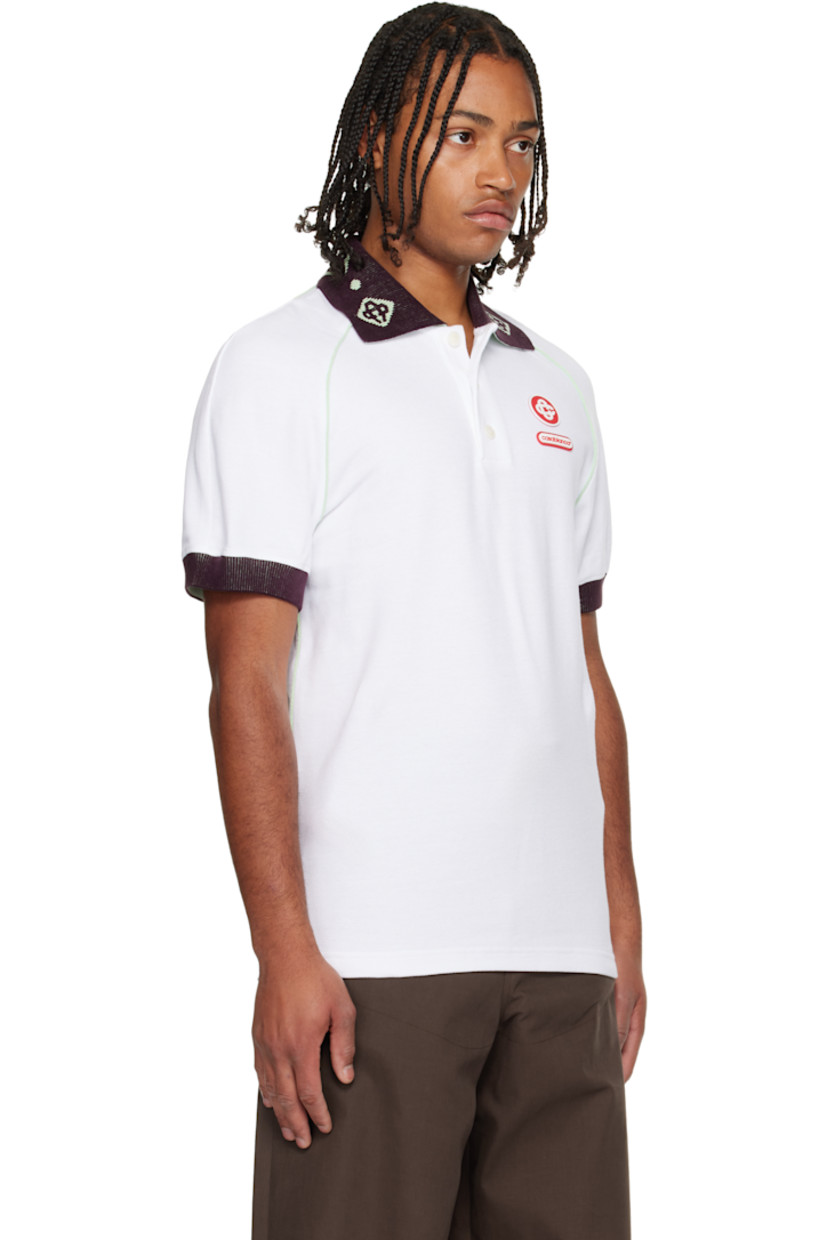 Textured cotton piqué polo.

· Piping throughout 
· Jacquard logo pattern at rib-knit chenille spread collar 
· Three-button placket 
· Rubber logo appliqués at chest and back collar 
· Vented side seams 
· Raglan sleeves 
· Rib-knit chenille cuffs

Supplier color: White