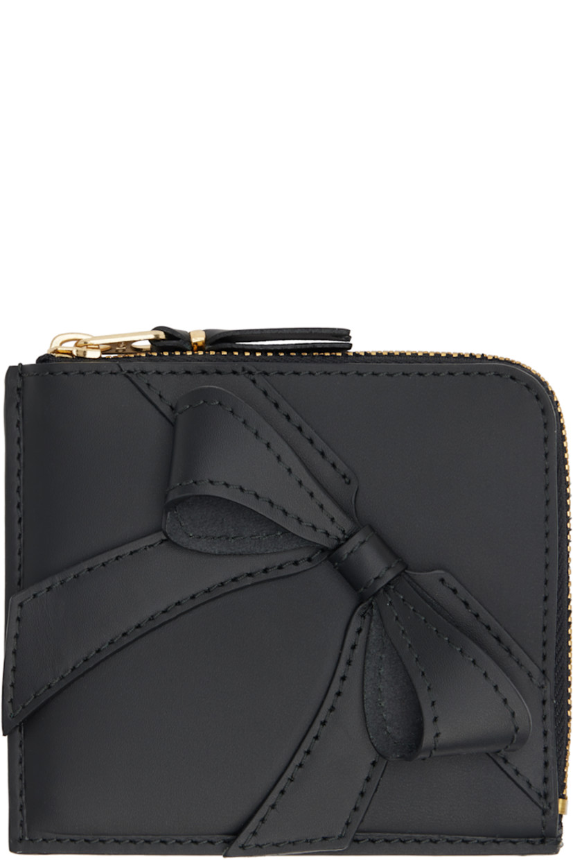 Buffed leather wallet in black. 

· Bow accent at face 
· Zip closure 
· Central note slot at interior
· Buffed leather lining
· H4" x W4.5" 

Supplier color: Black