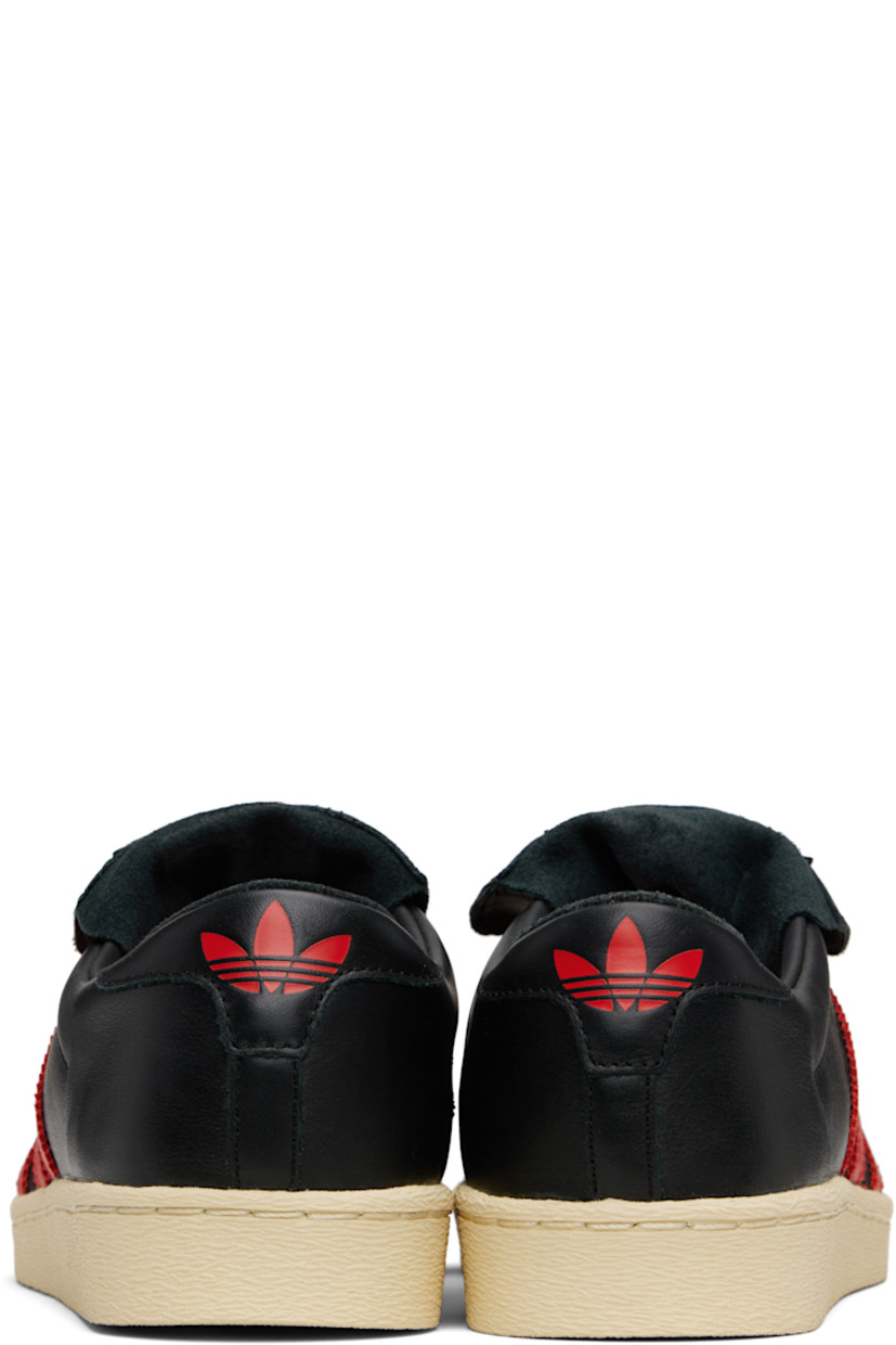 Low-top buffed leather sneakers.

· Textured rubber trim at toe
· Lace-up closure
· Logo patch at extended foldover tongue
· Padded collar
· Signature serrated stripes and perforations at sides
· Text embossed at outer side
· Logo embossed at heel tab
· Buffed leather lining
· Treaded rubber sole

Part of the Willy Chavarria x adidas Originals collaboration.

Supplier color: Black/Red