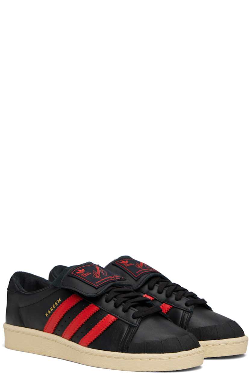 Low-top buffed leather sneakers.

· Textured rubber trim at toe
· Lace-up closure
· Logo patch at extended foldover tongue
· Padded collar
· Signature serrated stripes and perforations at sides
· Text embossed at outer side
· Logo embossed at heel tab
· Buffed leather lining
· Treaded rubber sole

Part of the Willy Chavarria x adidas Originals collaboration.

Supplier color: Black/Red