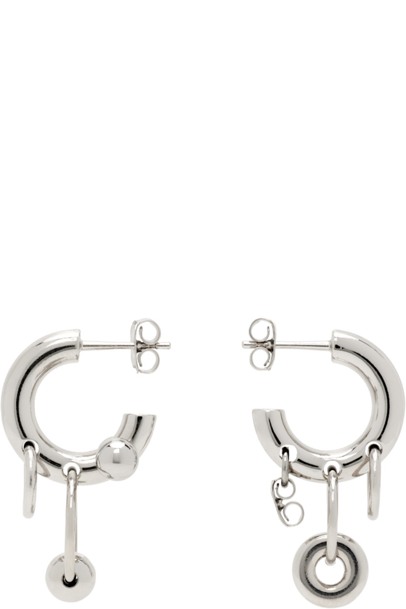 Pair of handcrafted open hoop earrings in palladium-plated brass.

· Mismatched charms at drop
· Post-stud fastening
· H1.25" x W0.75"

Supplier color: Palladium
