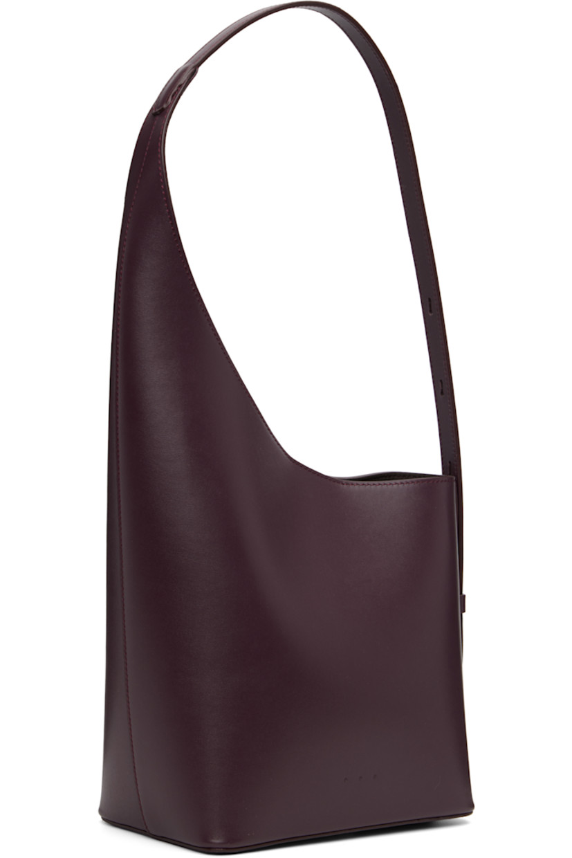 Buffed calfskin shoulder bag.

· Adjustable shoulder strap
· Logo embossed at face
· Magnetic closure
· Patch pocket at eco-suede interior
· H15.5" x W8" x D4.5"
· Total height: H18"

Supplier color: Fig