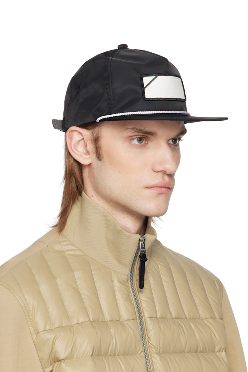 Nylon twill cap in black. 

· Graphic patch at face
· Braided piping at flat brim
· Logo embroidered at back face
· Faux-leather cinch fastening 
· Structured mesh panel at interior 
· Plain-woven browband
· Twill lining
· Logo-engraved black hardware

Supplier color: Black