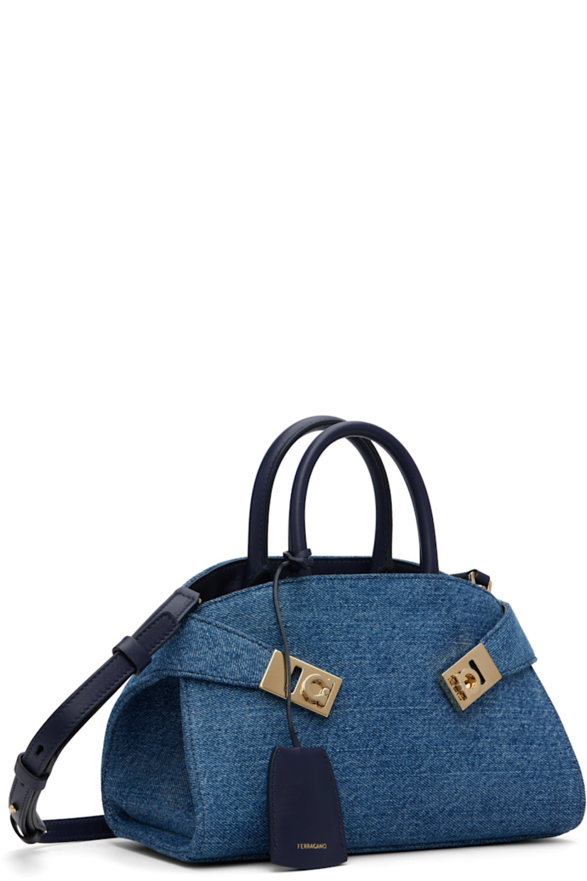 Denim top handle bag.

· Leather trim throughout
· Rolled carry handles
· Detachable sheathed keyring at handle
· Adjustable and detachable shoulder strap
· Flip-clasp strap at sides
· Patch pocket at interior
· H6” x W9” x D5”

Supplier color: Denim