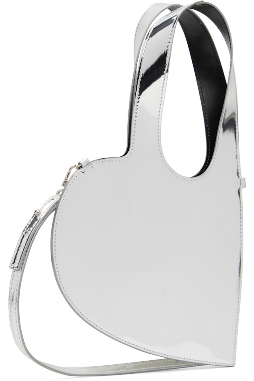 Heart-shaped patent faux-leather messenger bag.

· Integrated carry handles
· Adjustable and detachable crossbody strap
· H8.5" x W9"
· Total height: H13"

Supplier color: Silver