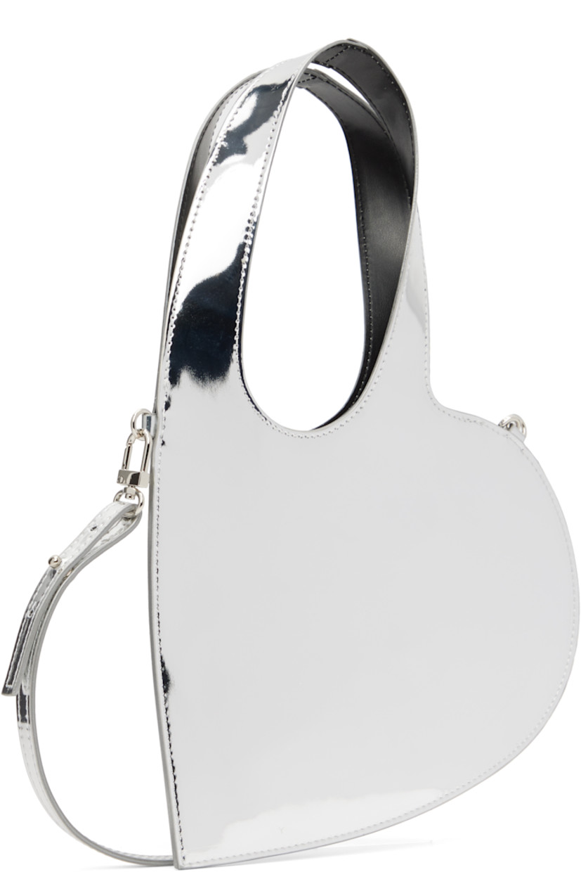 Heart-shaped patent faux-leather messenger bag.

· Integrated carry handles
· Adjustable and detachable crossbody strap
· H8.5" x W9"
· Total height: H13"

Supplier color: Silver