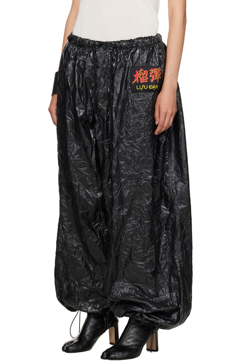 Resin-coated nylon sweatpants.

· Wide-leg 
· Drawstring at elasticized waistband 
· Two-pocket styling
· Button fly  
· Logo patch at front 
· Cord-lock drawstring at cuffs

Supplier color: Black