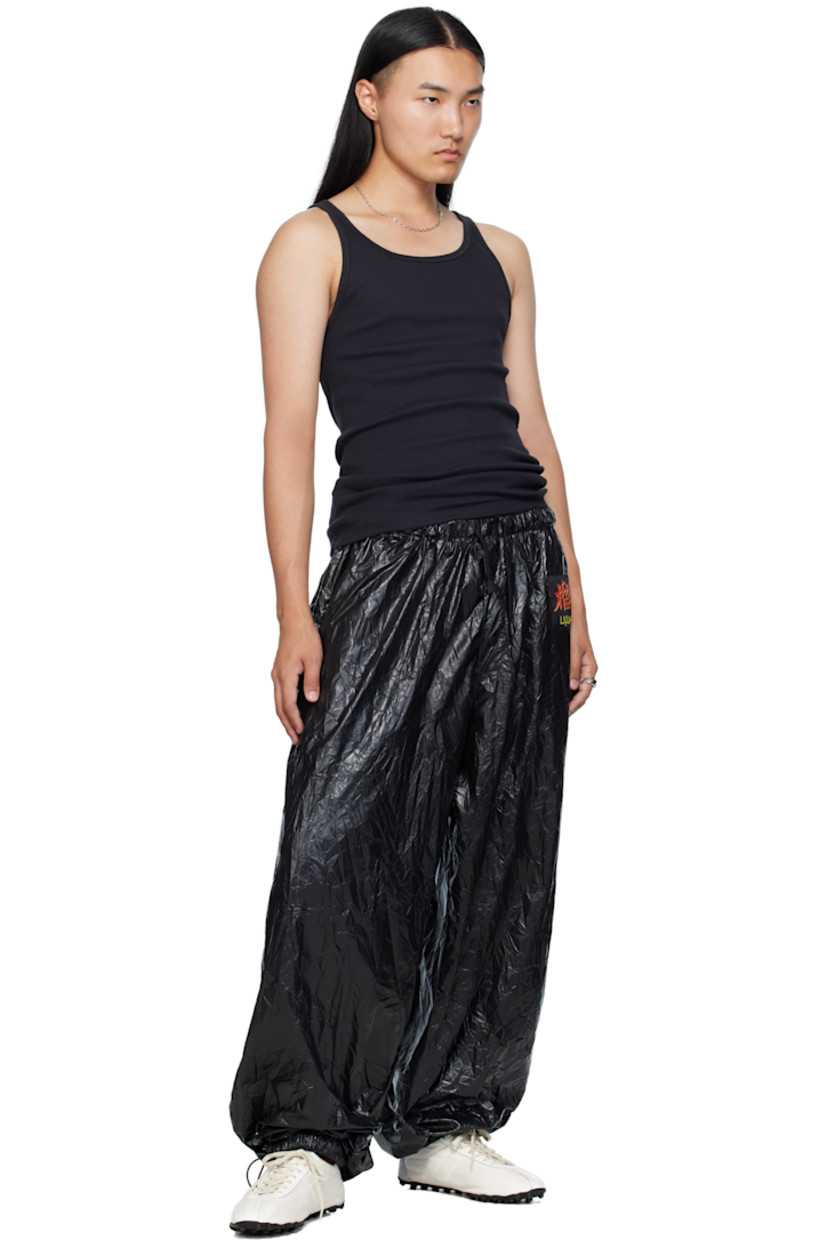 Resin-coated nylon sweatpants.

· Wide-leg 
· Drawstring at elasticized waistband 
· Two-pocket styling
· Button fly 
· Logo patch at front 
· Cord-lock drawstring at cuffs

Supplier color: Black