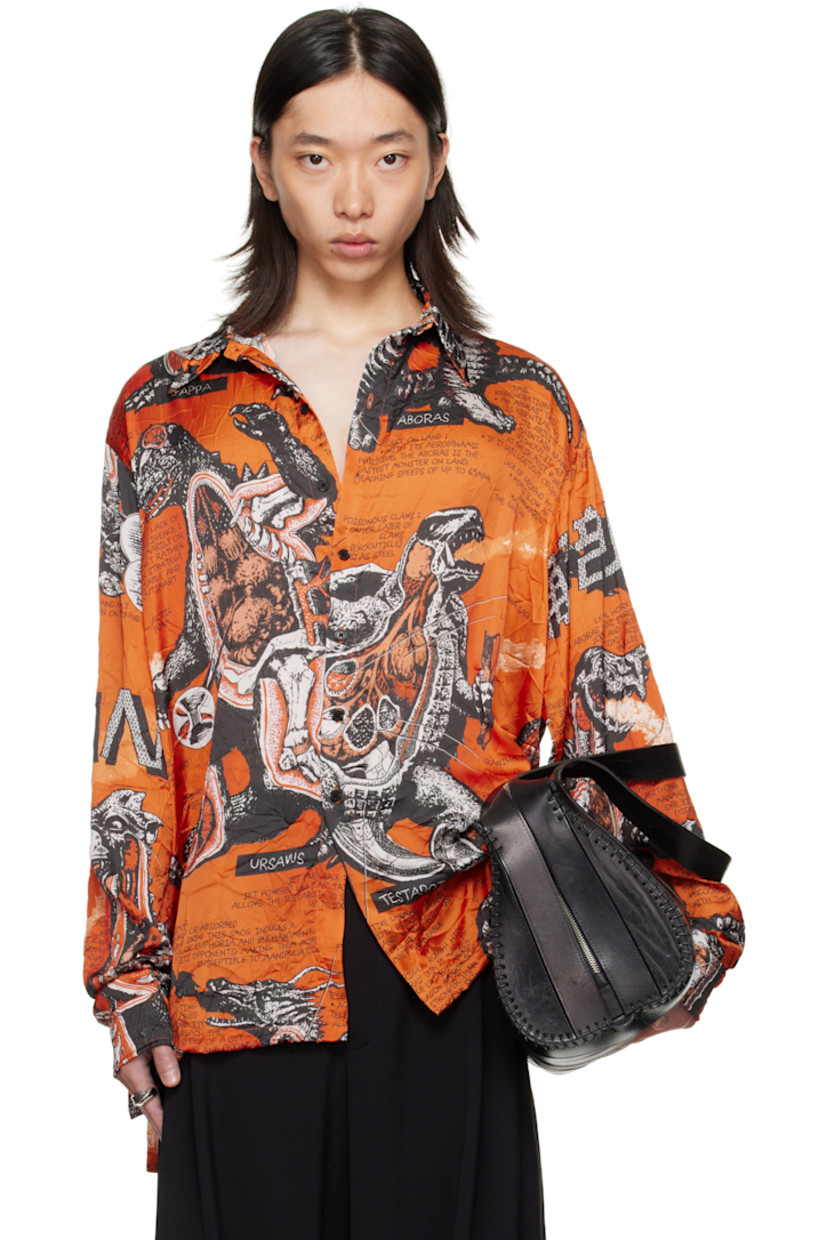 Crinkled satin shirt. 

· Graphics and texts printed throughout 
· Spread collar 
· Button closure
· Droptail hem 
· Vented side seams
· Dropped shoulders
· Buttoned barrel cuffs
· Box pleat at back yoke 

Supplier color: Monsters/Kumquat