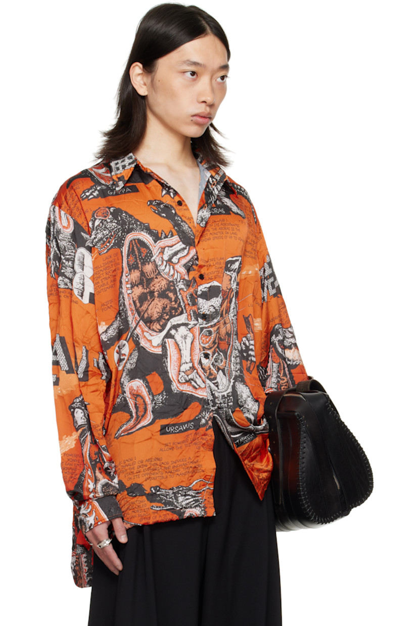 Crinkled satin shirt. 

· Graphics and texts printed throughout 
· Spread collar 
· Button closure
· Droptail hem 
· Vented side seams
· Dropped shoulders
· Buttoned barrel cuffs
· Box pleat at back yoke 

Supplier color: Monsters/Kumquat