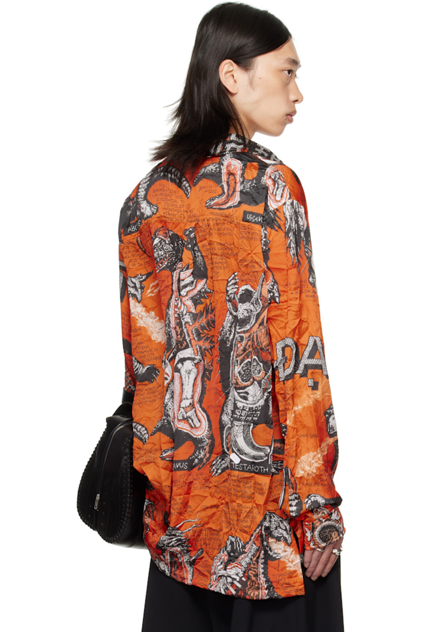 Crinkled satin shirt. 

· Graphics and texts printed throughout 
· Spread collar 
· Button closure
· Droptail hem 
· Vented side seams
· Dropped shoulders
· Buttoned barrel cuffs
· Box pleat at back yoke 

Supplier color: Monsters/Kumquat