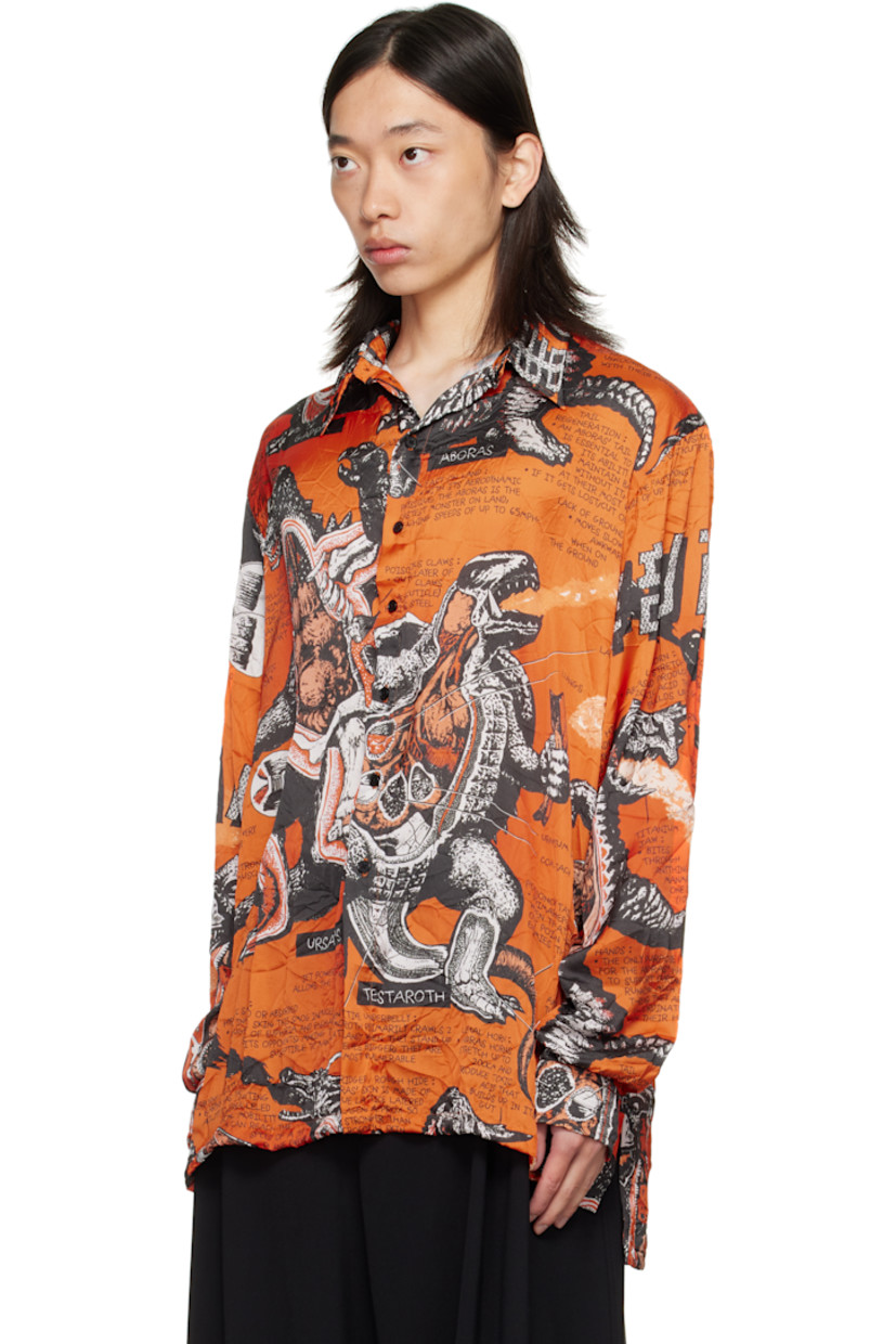 Crinkled satin shirt. 

· Graphics and texts printed throughout 
· Spread collar 
· Button closure
· Droptail hem 
· Vented side seams
· Dropped shoulders
· Buttoned barrel cuffs
· Box pleat at back yoke 

Supplier color: Monsters/Kumquat