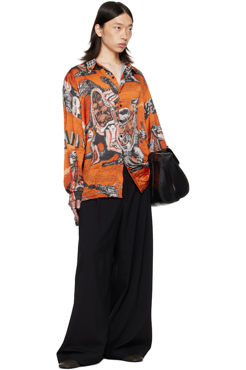 Crinkled satin shirt. 

· Graphics and texts printed throughout 
· Spread collar 
· Button closure
· Droptail hem 
· Vented side seams
· Dropped shoulders
· Buttoned barrel cuffs
· Box pleat at back yoke 

Supplier color: Monsters/Kumquat