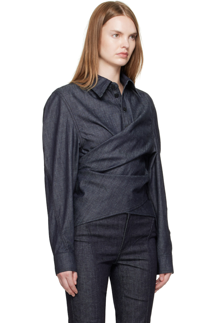 Organic cotton chambray shirt. 

· Wrap construction
· Pointed collar 
· Button placket at front
· Button closure at back
· Buttoned barrel cuffs
· Logo-engraved black hardware
· Contrast stitching in tan 

Supplier color: Raw blue