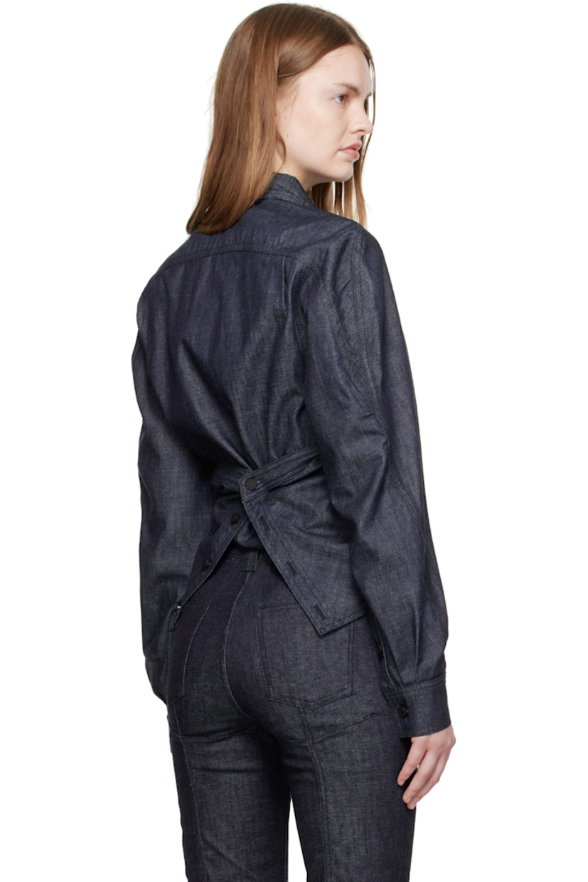 Organic cotton chambray shirt. 

· Wrap construction
· Pointed collar 
· Button placket at front
· Button closure at back
· Buttoned barrel cuffs
· Logo-engraved black hardware
· Contrast stitching in tan 

Supplier color: Raw blue