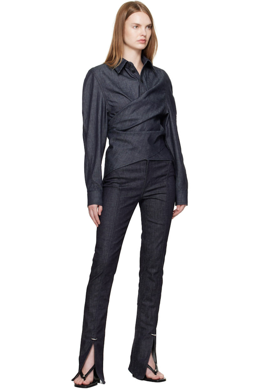Organic cotton chambray shirt. 

· Wrap construction
· Pointed collar 
· Button placket at front
· Button closure at back
· Buttoned barrel cuffs
· Logo-engraved black hardware
· Contrast stitching in tan 

Supplier color: Raw blue