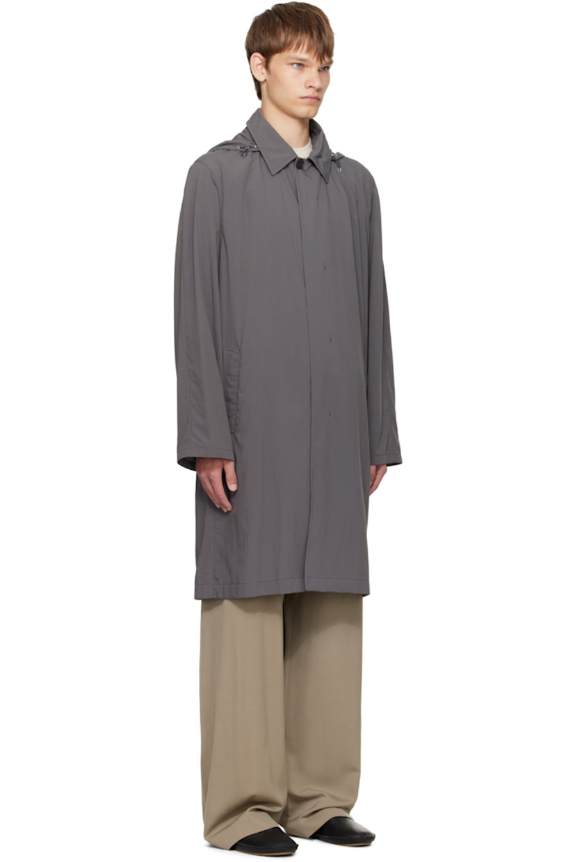 Crinkled nylon taffeta coat.

· Cord-lock drawstring at stowaway hood
· Spread collar 
· Button closure
· Welt pockets at waist
· Storm flap at back
· Zip pocket with detachable elasticized belt at back waist

Supplier color: Grey cobalt